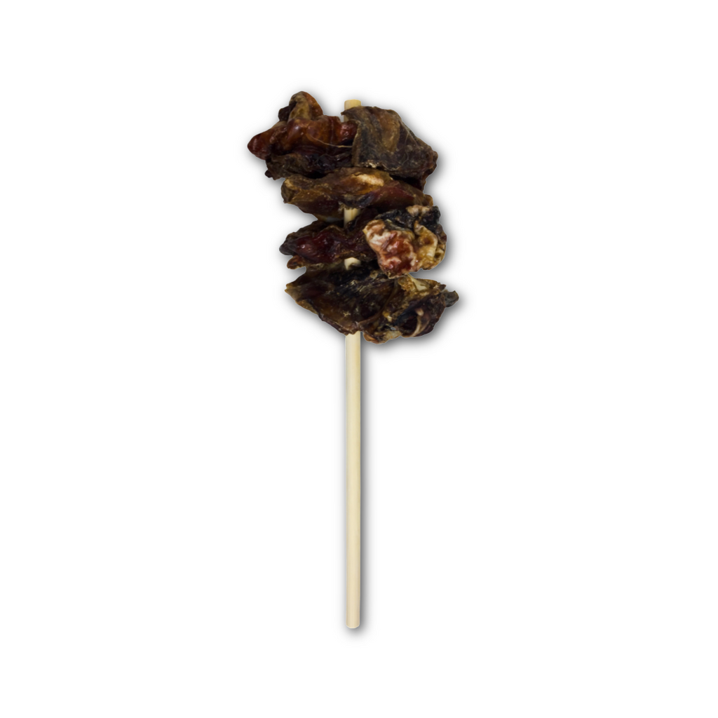 Chopped dark brown air dried beef testciles, on a wooden stick, on a white background.
