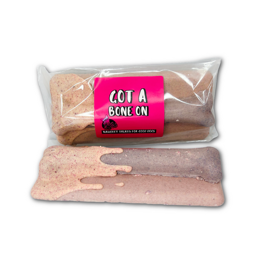 Pink/purple chocolate bars with a large bone shape - one in a packet with pink sticker saying 'Got a Bone On' in white writing ,the other below with no packaging. On a white background.